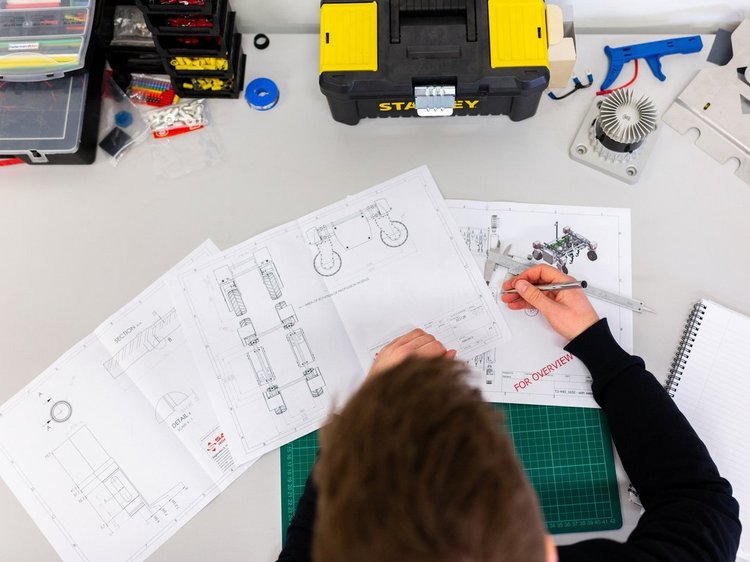 Das Foto zeigt eine Person mit technischen Zeichnungen