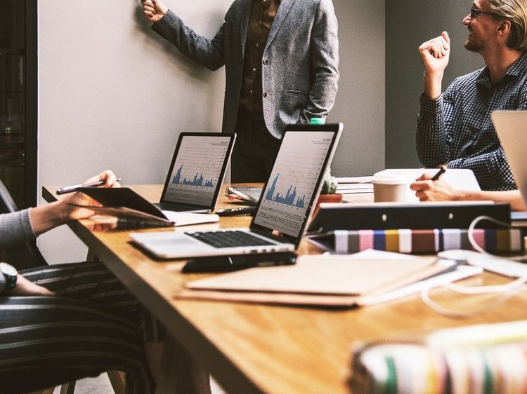 Das Foto zeigt drei menschen bei einer Teambesprechung