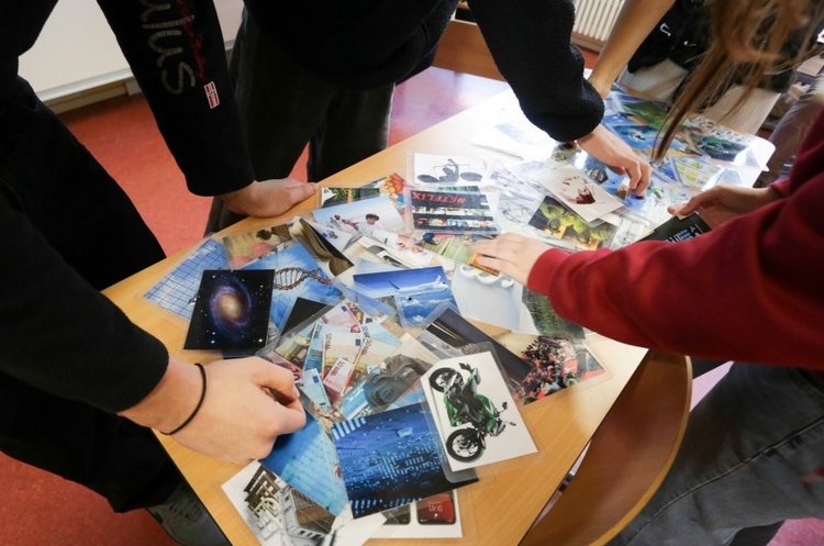Das Foto zeigt viele Hände, die sich am Tisch mit Infomaterial bedienen