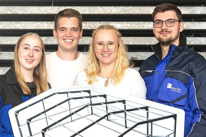 Das Foto zeigt vier junge Leute mit einem Modell einer Hallenkonstruktion
