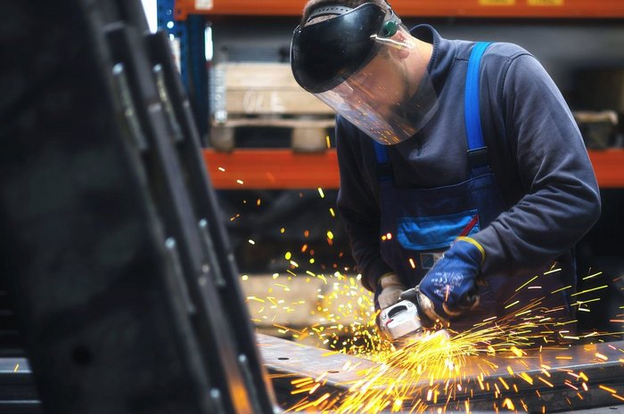 Das Foto zeigt einen jungen Mann bei der arbeit mit einer Flexmaschine