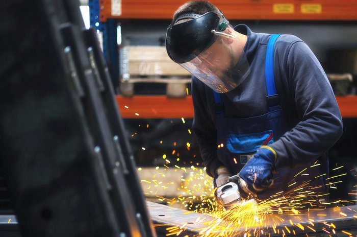 Das Foto zeigt einen jungen Mann bei der Arbeit mit einer Flexmaschine