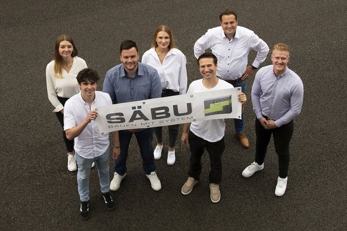 Das Foto zeigt 7 Mitarbeiter der SÄBU mit einer Fahne