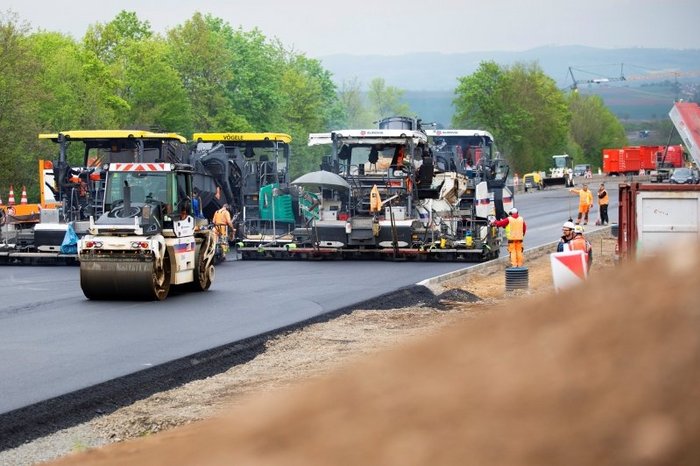 Das Foto zeigt große Straßenbaufahrzeuge beim Aufbringen einer Asphaltdecket